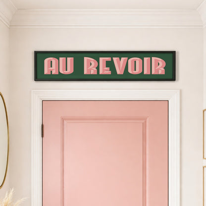 Au Revoir panoramic print in a black frame above a pink front door