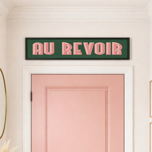 Au Revoir panoramic print in a black frame above a pink front door